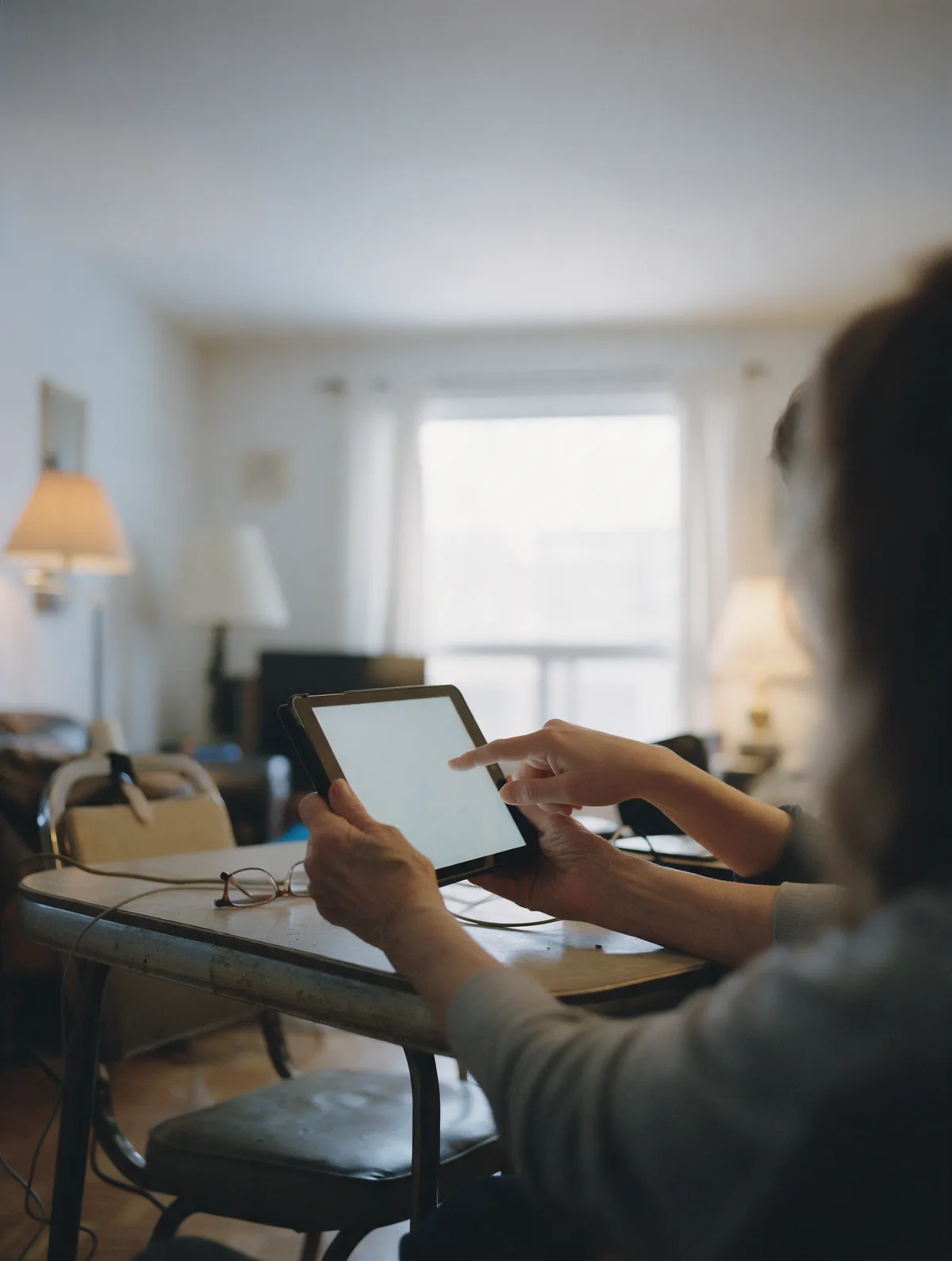 Un technicien patient explique une tablette à une dame âgée assise dans son salon.
